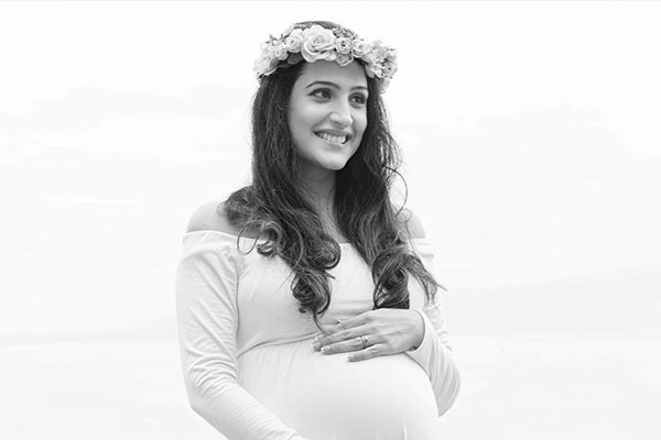 maternity photography of a radiant woman in a white dress holding her belly looking very happy
